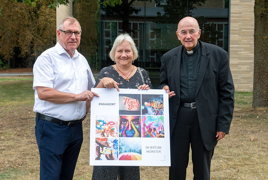 Ulrich Vollmer, Brigitte Lehmann und Bischof Felix Genn halten die neue Broschüre im Großformat in den Händen.