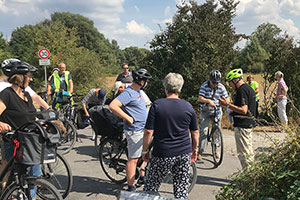 Auf einem Weg stehen mehrere Radfahrerinnen und Radfahrer.