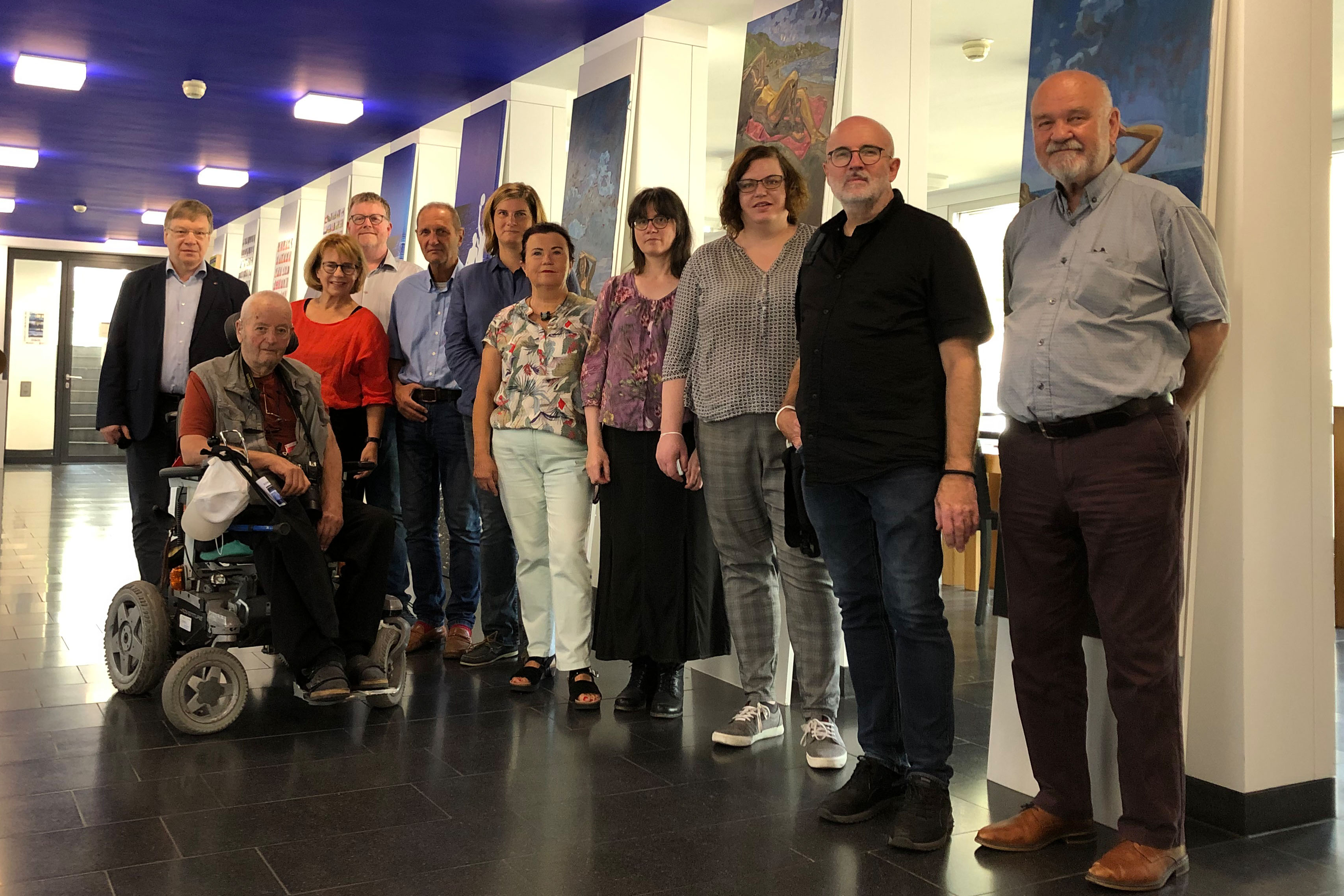 Gruppenbild der Künstler/innen und Veranstalter in der Ausstellung. Im Hintergrund sind einige Kunstwerke zu erkennen.