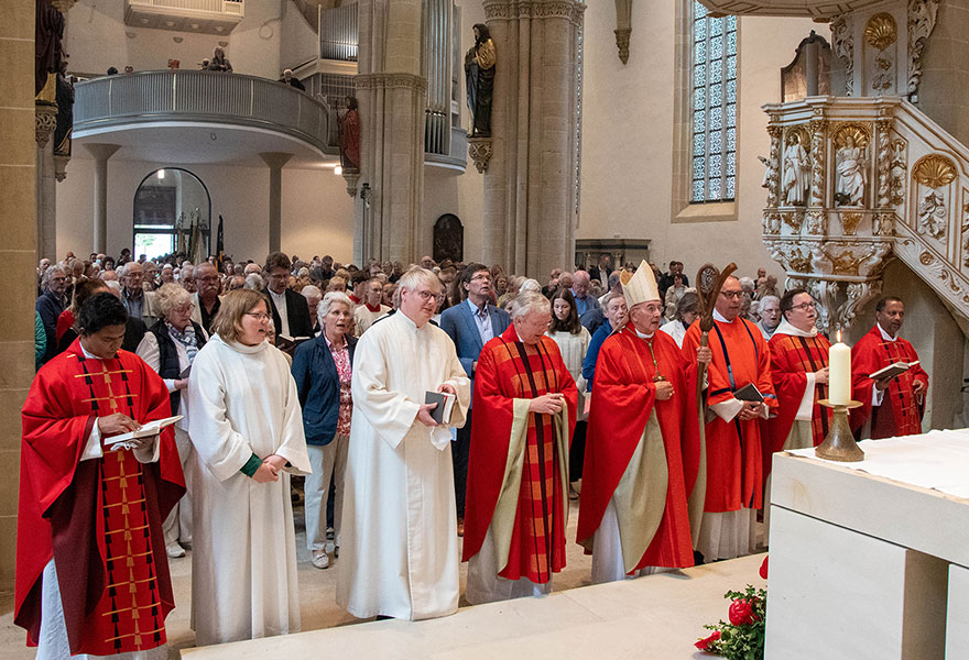 Seelsorgerinnen und Seelsorger stehen mit dem Bischof vor dem Altar.