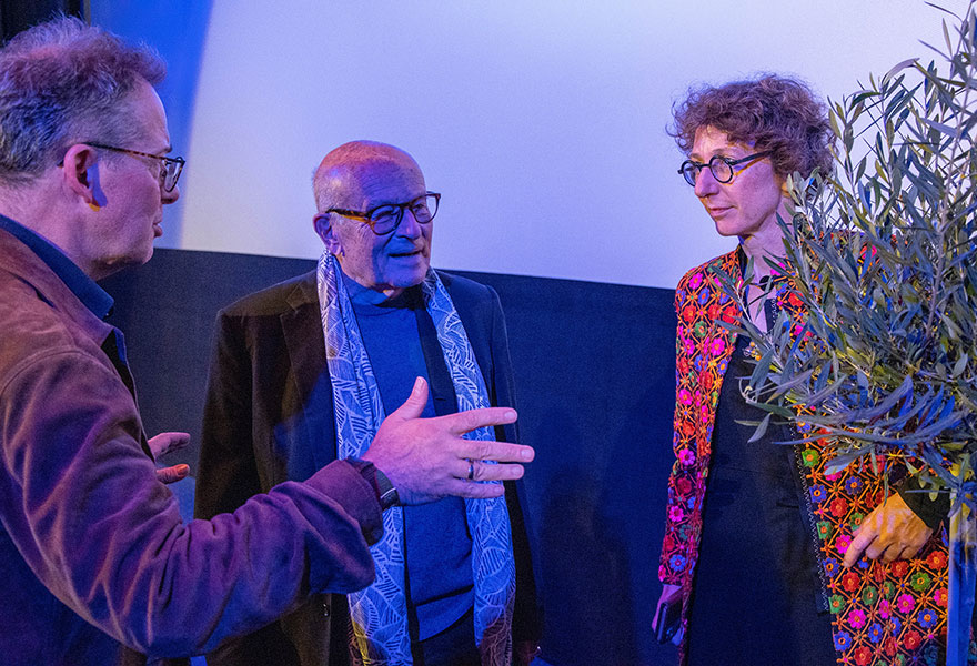 Künstlerischer Leiter Michael M. Kleinschmidt, Volker Schlöndorff und Laudatorin Prof. Dr. Julia Helmke (von links) stehen neben einem Olivenbaum und sprechen miteinander.
