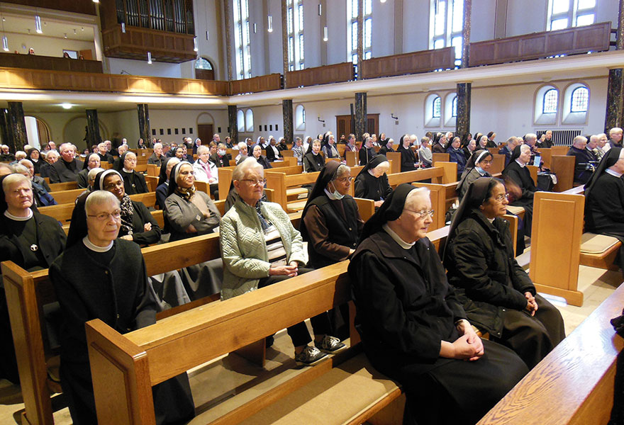 In einer Kirche sitzen zahlreiche Ordenschristen.