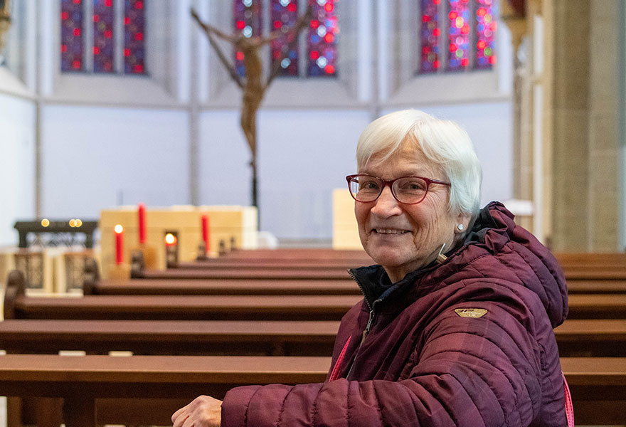 Porträt von Ursula Hüllen, die in der St.-Lamberti-Kirche in einer Bank sitzt.