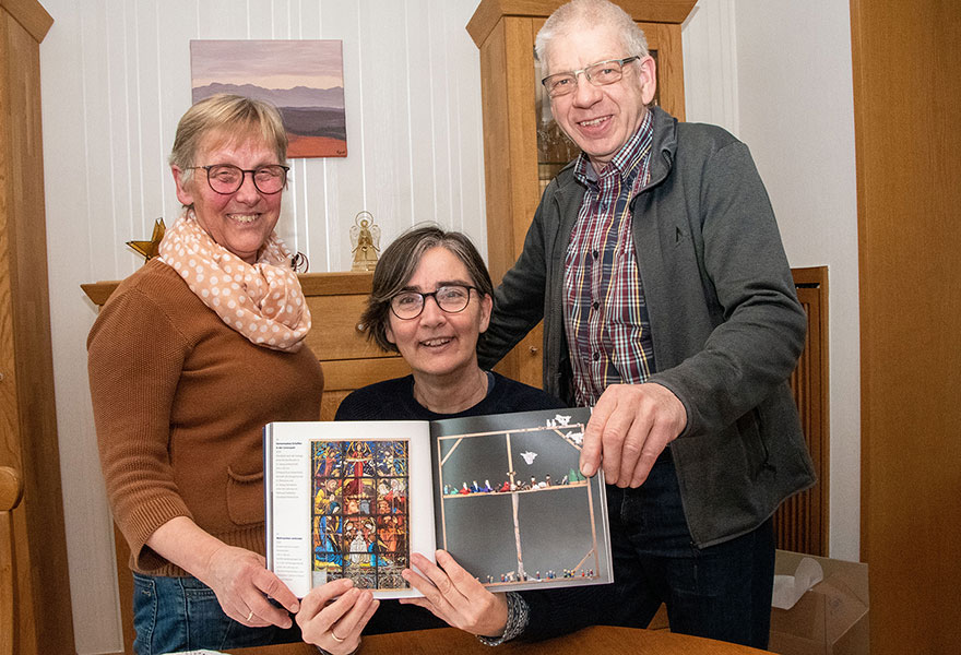 Waltraud Holtkötter, Petra Schäfers und Albin Holtkötter halten den Katalog der Krippenausstellung in der Hand.