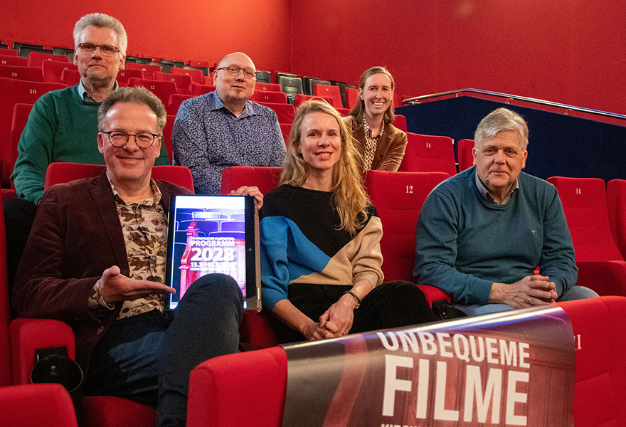 Das Festivalteam sitzt im Kino und lächelt in die Kamera.