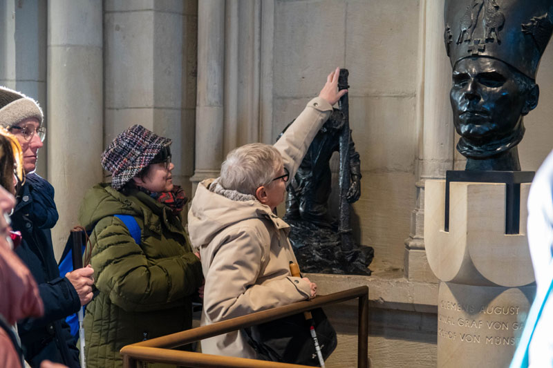 Beim Kreuzweg von Bert Gerresheim haben die Teilnehmerinnen die Möglichkeit, die Bronzefiguren im Domumgang zu ertasten.