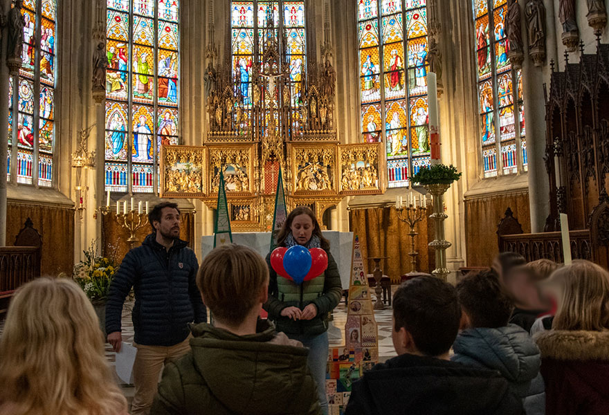 Sarah Tammen steht vor den Schülerinnen und Schülern und hält drei Luftballons in der Hand.