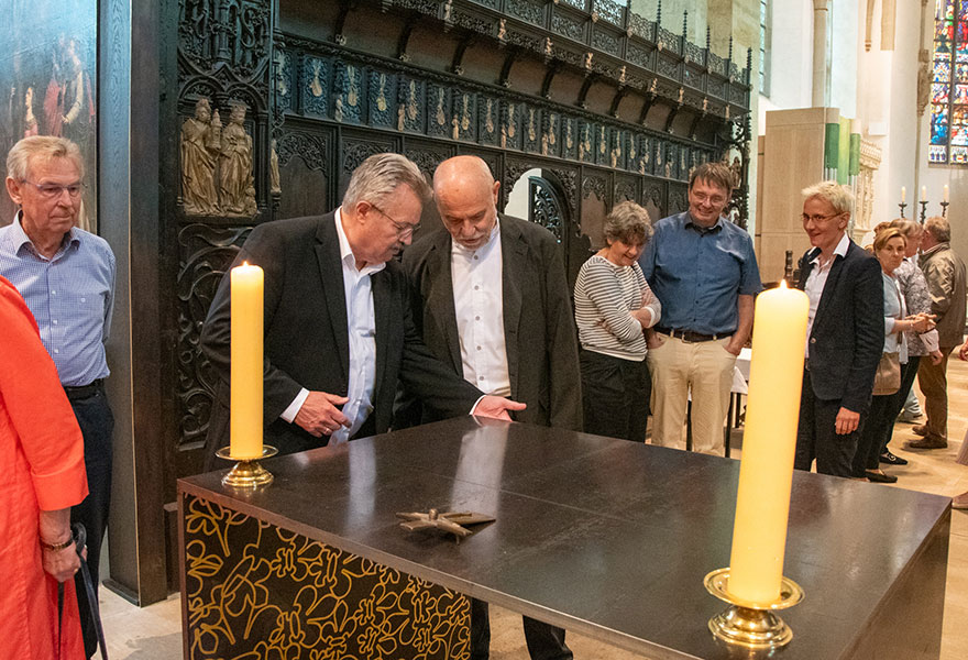 Zwei Männer stehen an dem Altar aus Stahl und unterhalten sich darüber.