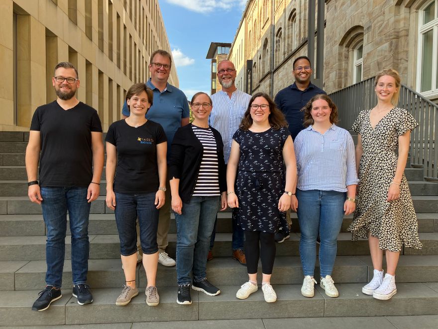 Daniel Werner, Charlotte Nielen, Juliane Rolf, Anna Lisa Volkmar, Eva Brambrink, Verena Oelerich, hintere Reihe von links Stefan Uerlings, Marko Weibels und Sampras Jesurasa stehen auf einer Treppe am für Diakonat und pastorale Dienste in Münster.