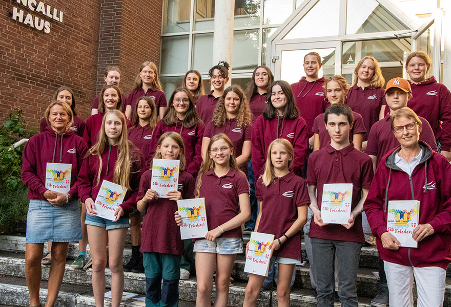 Die Sängerinnen und Sänger haben ihre roten Chor-T-Shirts an und sich zum Gruppenbild auf einer Treppe aufgestellt.