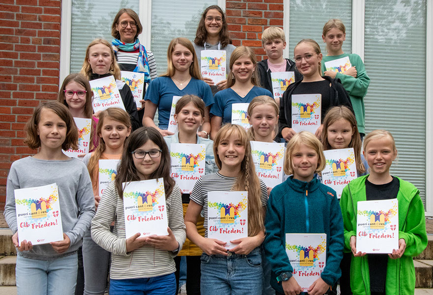 Die jungen Menschen haben sich auf einer Treppe zum Gruppenbild aufgestellt und halten das Chorbuch von Pueri Cantores in der Hand.