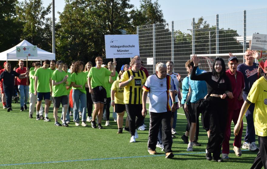 Mit Schildern und Bannern ziehen die Sportlerinnen und Sportler in das Stadion ein.