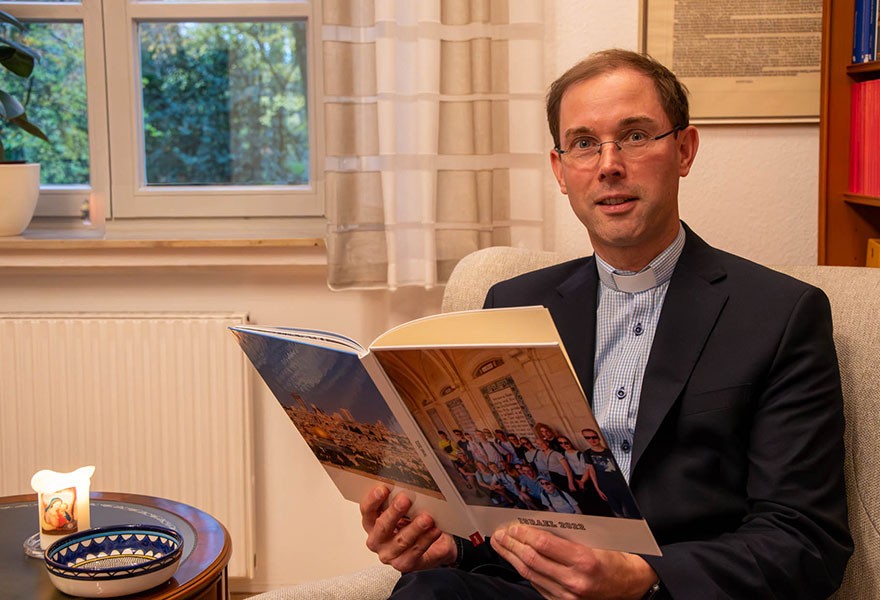 Oliver Rothe sitzt in einem Sessel und hat ein Fotobuch über Israel in der Hand.