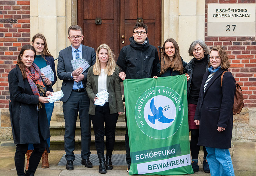 Mehrere Personen, zwei davon halten eine grüne Fahne mit der Aufschrift - Christians for Future - Schöpfung bewahren