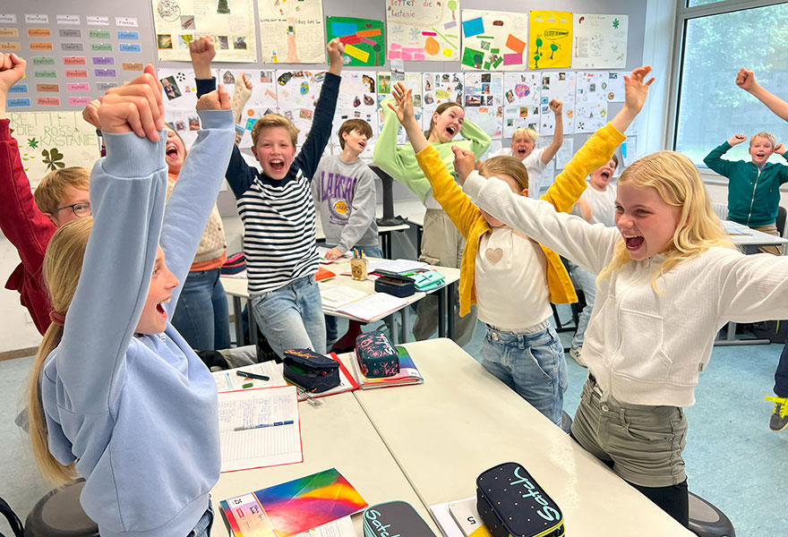 Schülerinnen und Schüler jubeln im Klassenzimmer.