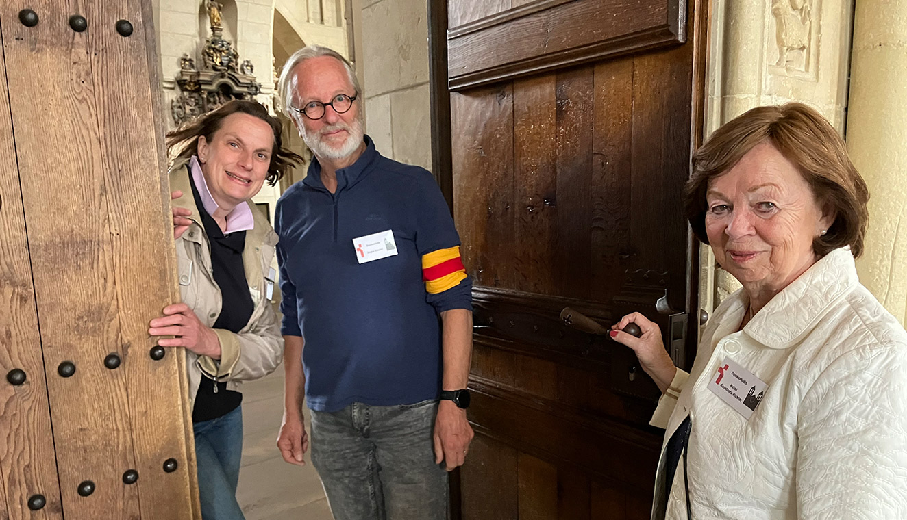 Drei Personen die in der Eingangstür. Sie heißen Menschen im St.-Paulus-Dom Münster willkommen: die ehrenamtlichen Domkustoden Maria Schulze Bölling (von links), Jürgen Stockel und Helmi Aenstoots-Richter.