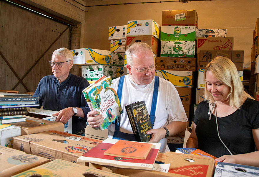 Drei Menschen sortieren Bücher.