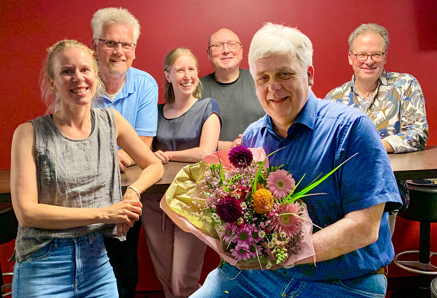 Joachim van Eickels hält im Vordergrund einen Blumenstrauß fest. Das Team steht hinter ihm.