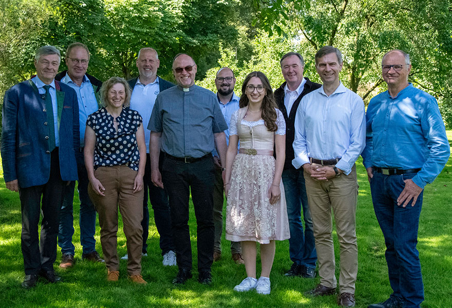 Die Gesprächsteilnehmer stellen sich unter schattigen Bäumen zum Gruppenbild auf.
