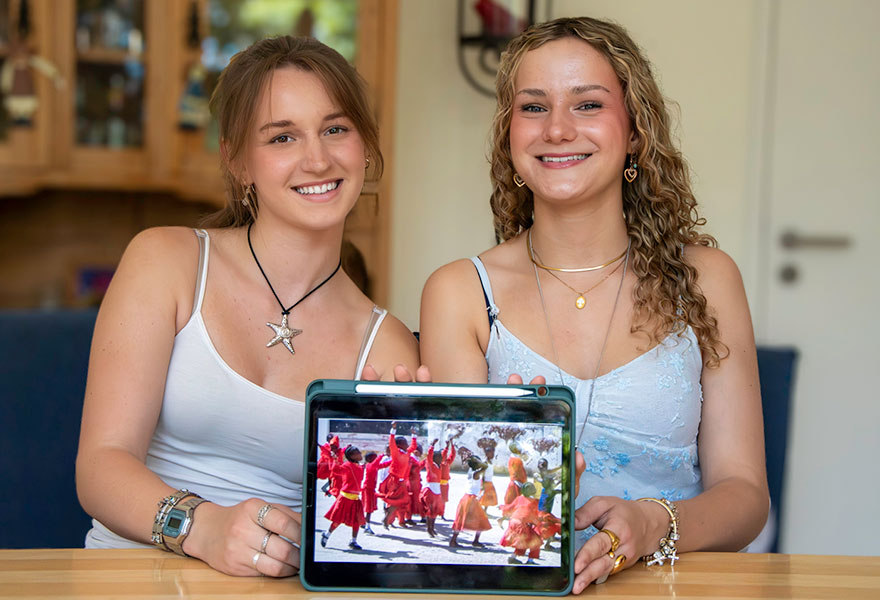 Die beiden jungen Frauen halten ein Tablett mit einem Foto aus ihrem Projekt in die Kamera.
