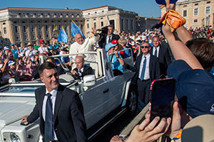 Die Menschen winken dem Papst zu, der im Papamobil sitzt.