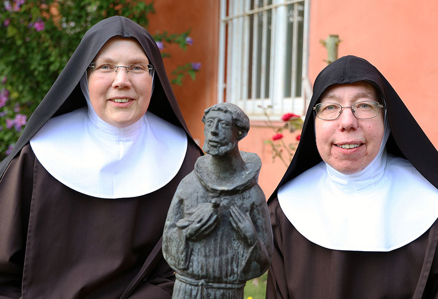 Die beiden Schwestern stehen in ihrer Ordenstracht nebeneinander und lächeln in die Kamera.