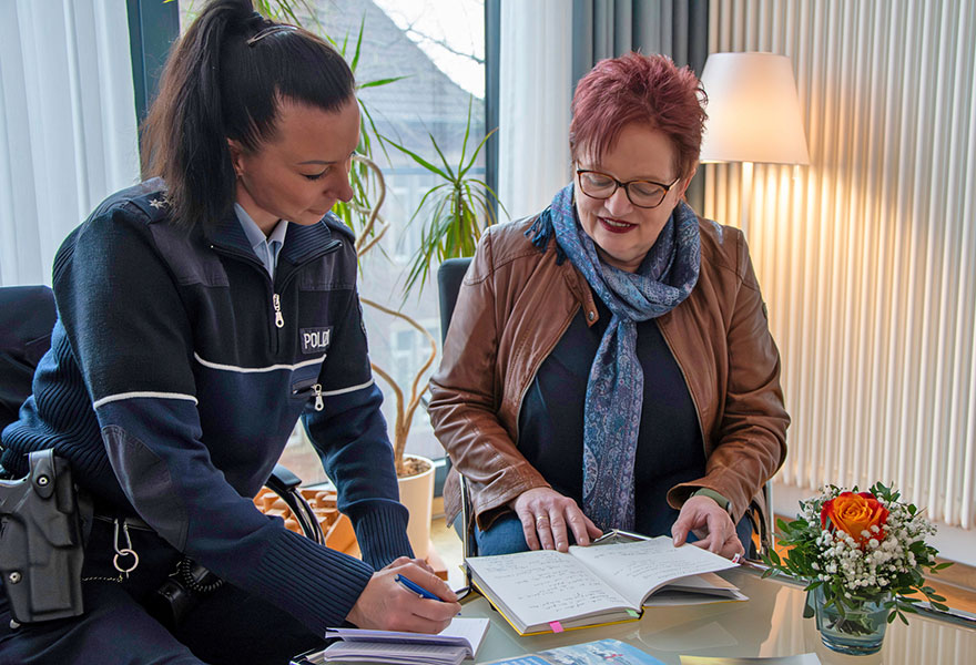 Zwei Frauen sitzen nebeneinander und schauen in ein Notizbuch.