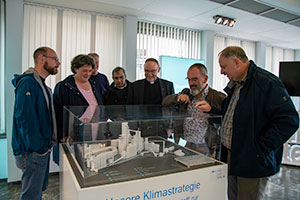 Mehrere Personen stehen an einem Modell und unterhalten sich darüber.