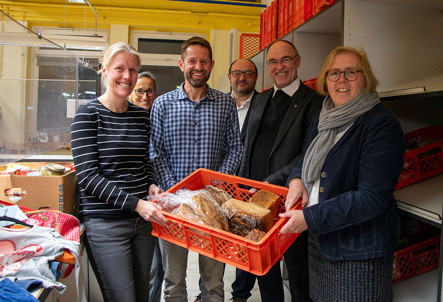 Die Gruppe steht gemeinsam hinter dem Verkaufstresen der Tafel. 