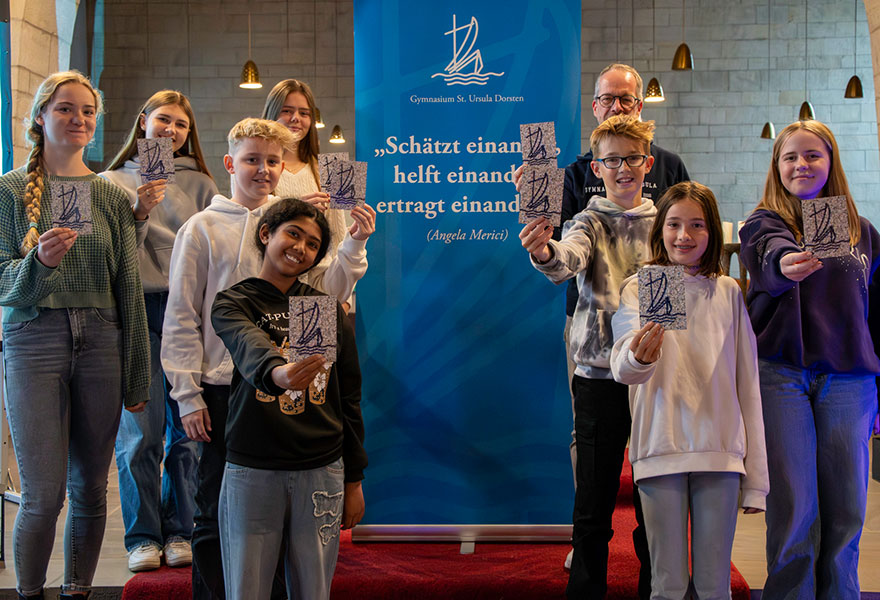 Die Schülerinnen und Schüler halten eine Postkarte in die Kamera.
