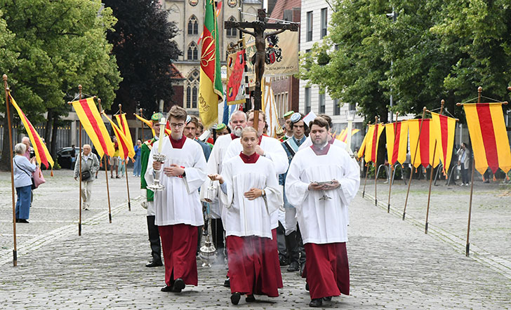 Messdiener mit Kreuz und Weihrauch führen die Prozession auf dem Domplatz an. 