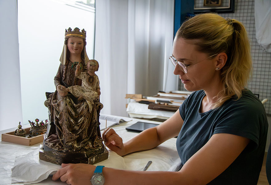 Vor der Restauratorin steht die Marienfigur, die sie vorsichtig bearbeitet Vor der Restauratorin steht die Marienfigur, die sie vorsichtig bearbeitet