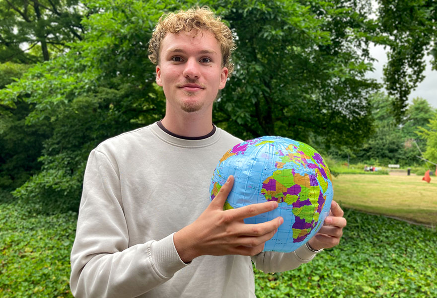 Clemens Große Erdmann hat eine aufblasbare Weltkugel in der Hand und zeigt auf Ghana.