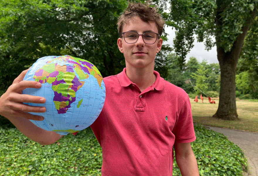 Jaspar Merz hält eine aufblasbare Weltkugel in der Hand und zeigt auf Ghana.