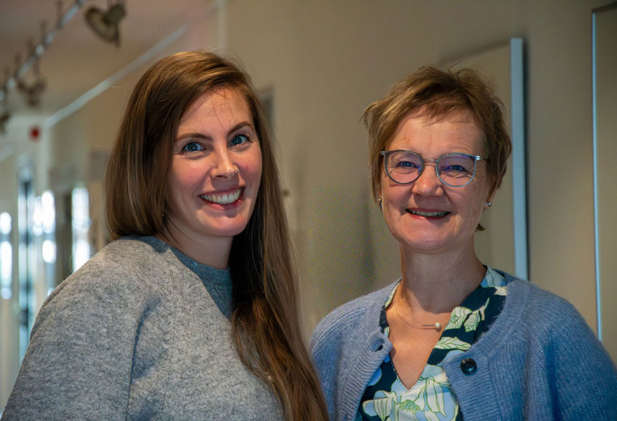 Die beiden Frauen stehen nebeneinander und lächeln in die Kamera.
