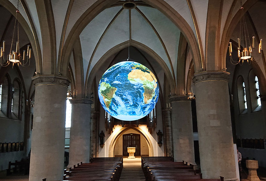 Eine große Erdkugel scheint unter dem Gewölbe der Kirche zu schweben.