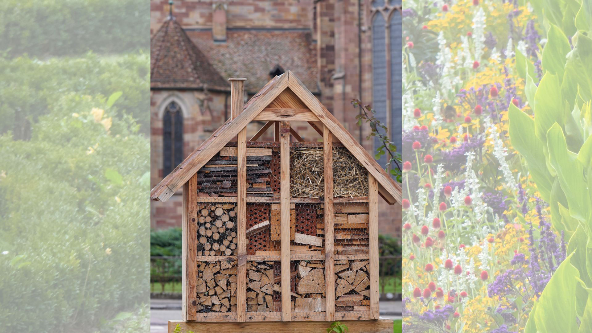 Ein großes Insektenhotel aus Holz steht im Freien. Es ist in mehrere Fächer unterteilt, die mit Naturmaterialien wie Holzstücken, Stroh und Ziegeln gefüllt sind. Im Hintergrund ist unscharf eine Kirchenfassade zu sehen. Ein großes Insektenhotel aus Holz steht im Freien. Es ist in mehrere Fächer unterteilt, die mit Naturmaterialien wie Holzstücken, Stroh und Ziegeln gefüllt sind. Im Hintergrund ist unscharf eine Kirchenfassade zu sehen.