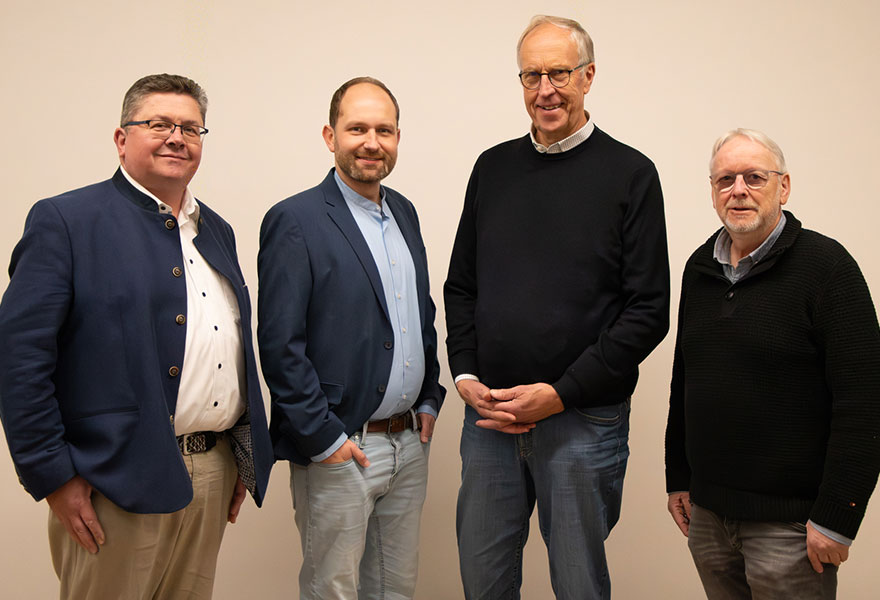 Die vier Mitglieder stehen nebeneinander und lächeln in die Kamera.