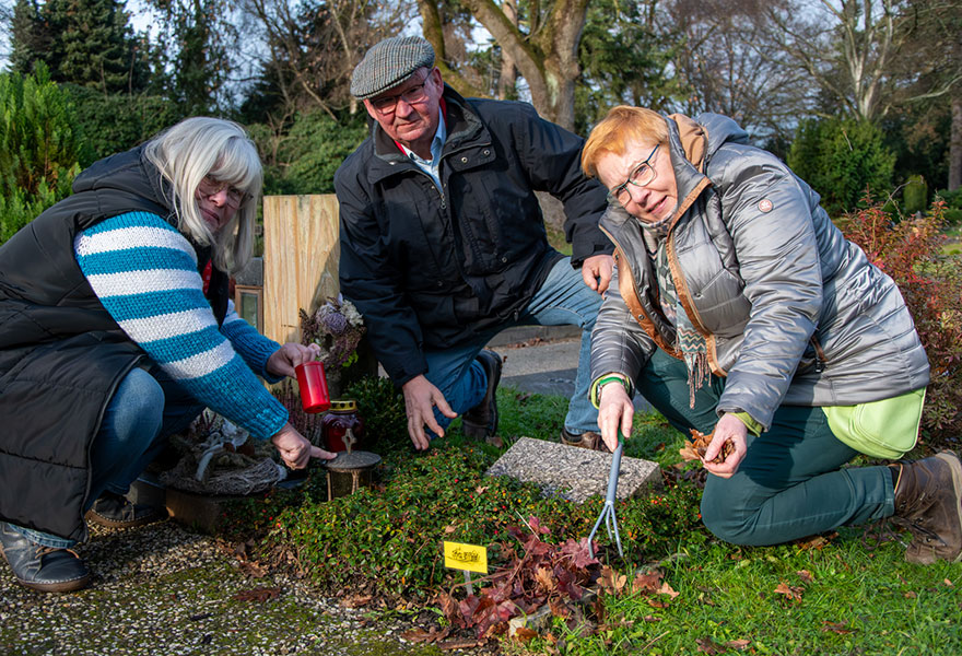 Die drei Aktiven säubern ein Urnengrab.