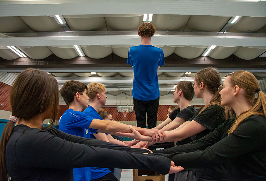 Ein Jugendlicher lässt sich rückwärts fallen, hinter ihm stehen weitere Jugendliche, die ihn auffangen.