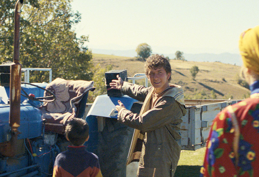 Ein Junge steht an einem Trecker mit einer Box und schaut eine Frau an.