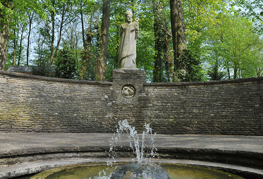 Vorne sprudelt Wasser aus dem Ludgerusbrunnen, im Hintergrund ist die Ludgerusfigur zu sehen.