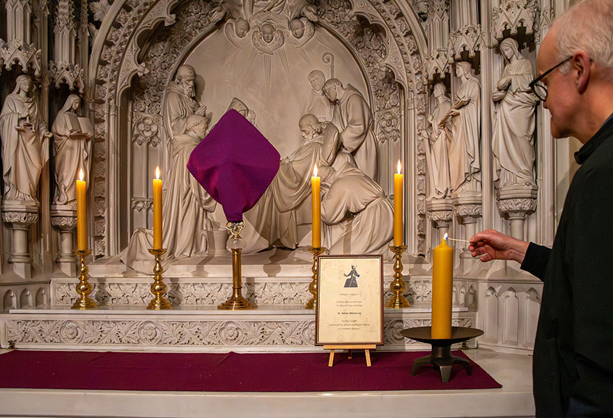 Propst Serries entzündet am Altar eine Kerze.