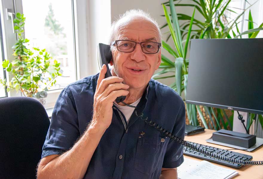 Porträt von Peter Braukmann, der einen Telefonhörer am Ohr hält.
