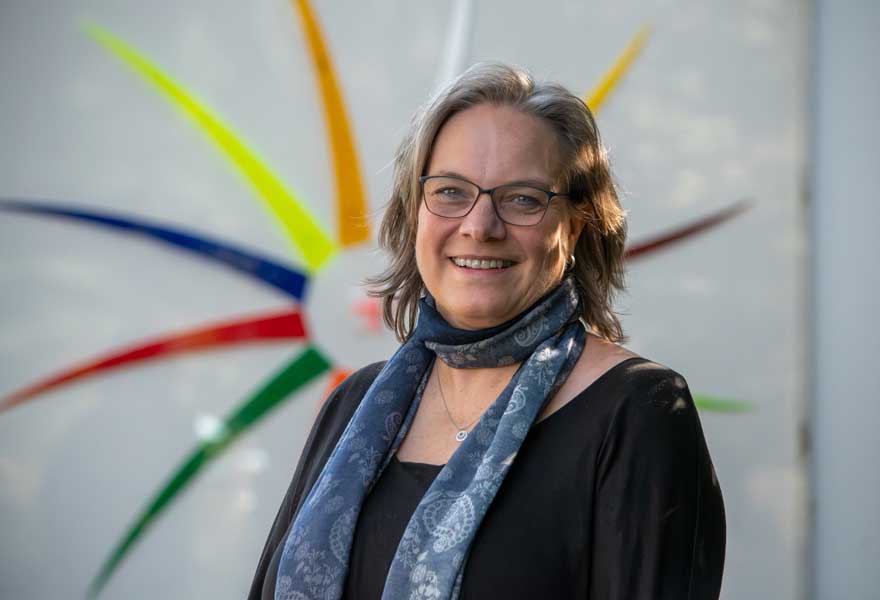 Porträt von Ursula Jesussek vor dem Logo der Schule, das eine Sonne mit bunten Strahlendarstellt. Porträt von Ursula Jesussek vor dem Logo der Schule, das eine Sonne mit bunten Strahlendarstellt.