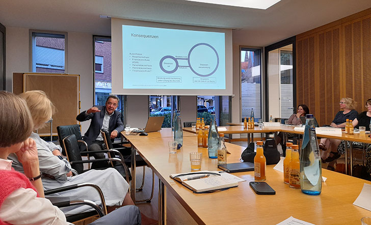 In einem Konferenzraum sitzt eine Gruppe von Frauen, die einem Mann zuhören, der gerade eine Präsentation vorstellt In einem Konferenzraum sitzt eine Gruppe von Frauen, die einem Mann zuhören, der gerade eine Präsentation vorstellt