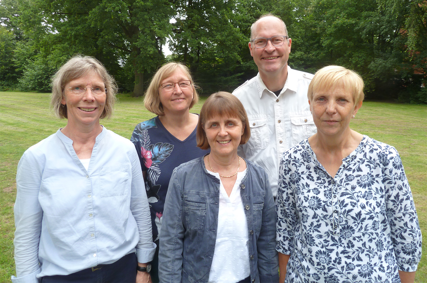 Vier Frauen und ein Mann stehen auf einer Rasenfläche. Im Hintergrund sind Bäume. Vier Frauen und ein Mann stehen auf einer Rasenfläche. Im Hintergrund sind Bäume.