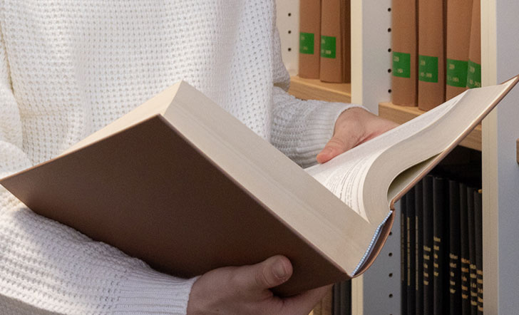 Jemand hält ein sehr großes Buch in den Händen.
