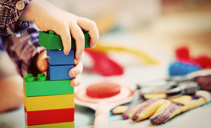 Symbolbild: Kinderhände bauen einen kleinen Lego Turm.