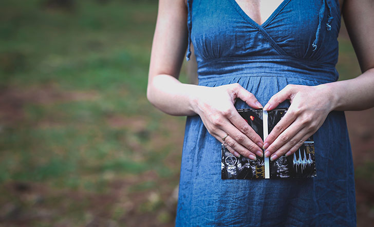 Eine schwangere Frau formt ein Herz über ihrem Bauch